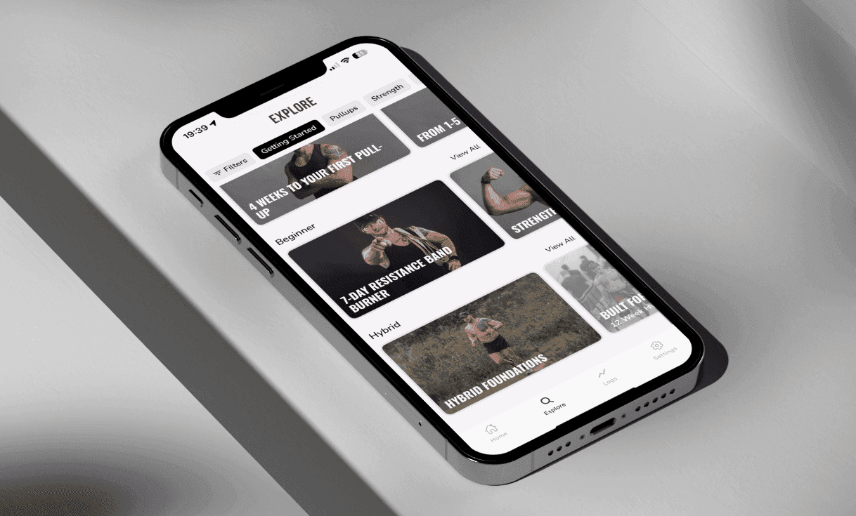 Smartphone displaying a fitness app with various workout programs and categories on the screen.